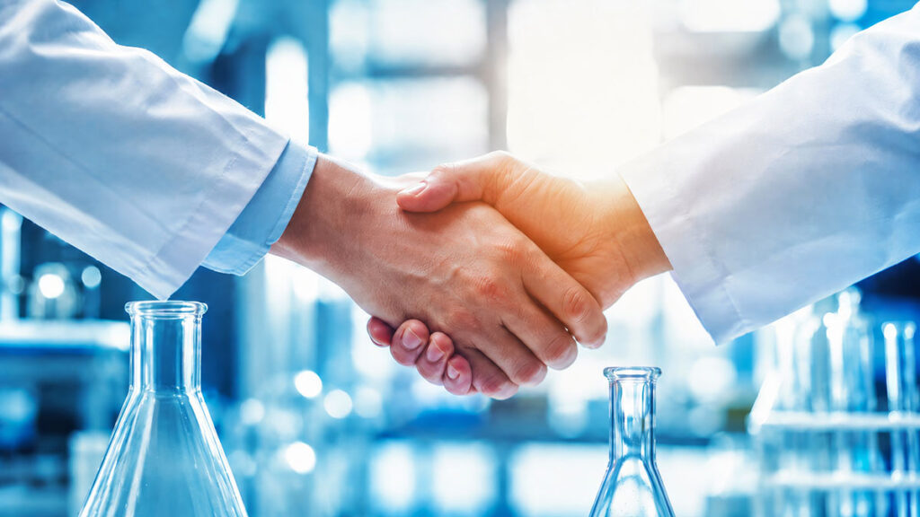 men in lab coats shaking hands in lab with lab equipment on counters